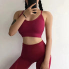 Woman in red sportswear set with decorative back stripes, posing against a white background. Fitness apparel, activewear, stylish gym outfit.