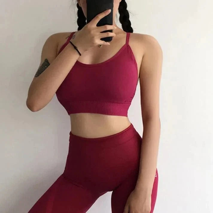 Woman in red sportswear set with decorative back stripes, posing against a white background. Fitness apparel, activewear, stylish gym outfit.