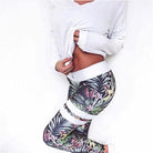 Woman wearing floral patterned leggings and a white long-sleeve top, showcasing stylish activewear. Fashionable workout outfit, floral sportswear.
