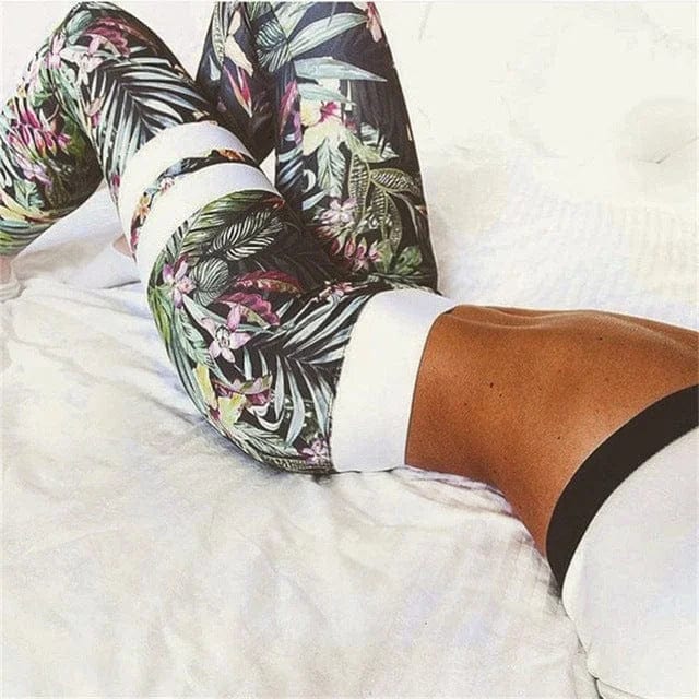 Woman wearing floral patterned green leggings, lying on a white bed. Trendy activewear, stylish workout outfit, floral leggings fashion.