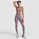 Woman in lavender sportswear set, featuring a classic cut sports bra and high-waisted leggings, paired with white sneakers. Fitness fashion.