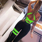 Woman wearing a green striped one-piece sports jumpsuit, showcasing fitness fashion. Ideal for gym workouts and active lifestyle enthusiasts.