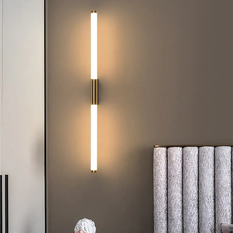 Modern vertical LED wall sconce with dual light tubes on a gray wall, next to a textured curtain. Stylish home lighting fixture.