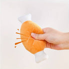 Hand squeezing a plush toy shaped like a cartoon chicken drumstick, with sound effects. Soft, orange, novelty stress relief toy for kids and adults.