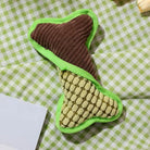 Dog chew toy shaped like a bone with textured brown and green fabric, placed on a green checkered cloth. Durable pet toy for interactive play.