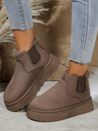 Brown suede ankle boots with faux fur lining and elastic side panels, paired with light blue skinny jeans. Stylish winter footwear for women.