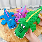 Colorful plush crocodile toys on a wooden table, featuring blue, purple, and green designs with playful eyes, perfect for kids' gifts and decor.