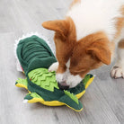 Dog playing with a green plush alligator toy on wooden floor, interactive pet toy, durable chew toy for dogs, fun pet accessory.