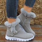 Gray suede winter boots with faux fur lining, side zipper, and white rubber soles, paired with frayed hem jeans on wooden floor background.