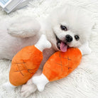 Fluffy white Pomeranian dog playing with plush toy drumsticks on a soft white rug, showcasing cute pet accessories and playful dog behavior.