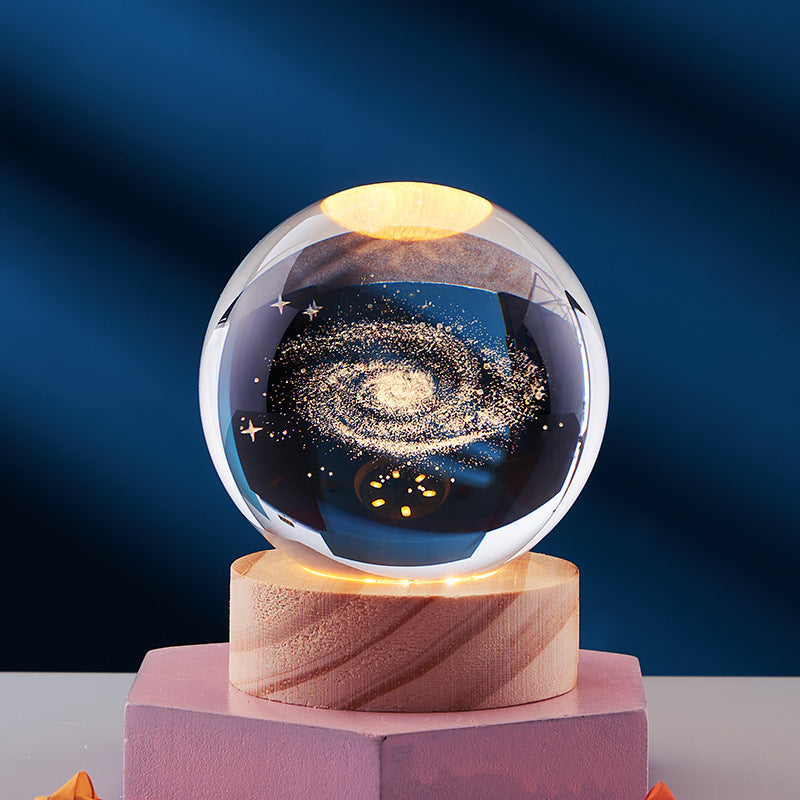 Crystal ball with galaxy design on wooden base, illuminated by LED light. Perfect for home decor, gifts, and enhancing modern interior aesthetics.