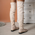 Beige over-the-knee suede boots with side zippers, showcased in a stylish indoor setting, perfect for fall fashion and trendy footwear enthusiasts.