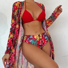 Woman modeling vibrant floral bikini set with matching cover-up, featuring red and tropical patterns. Perfect for beachwear fashion trends.