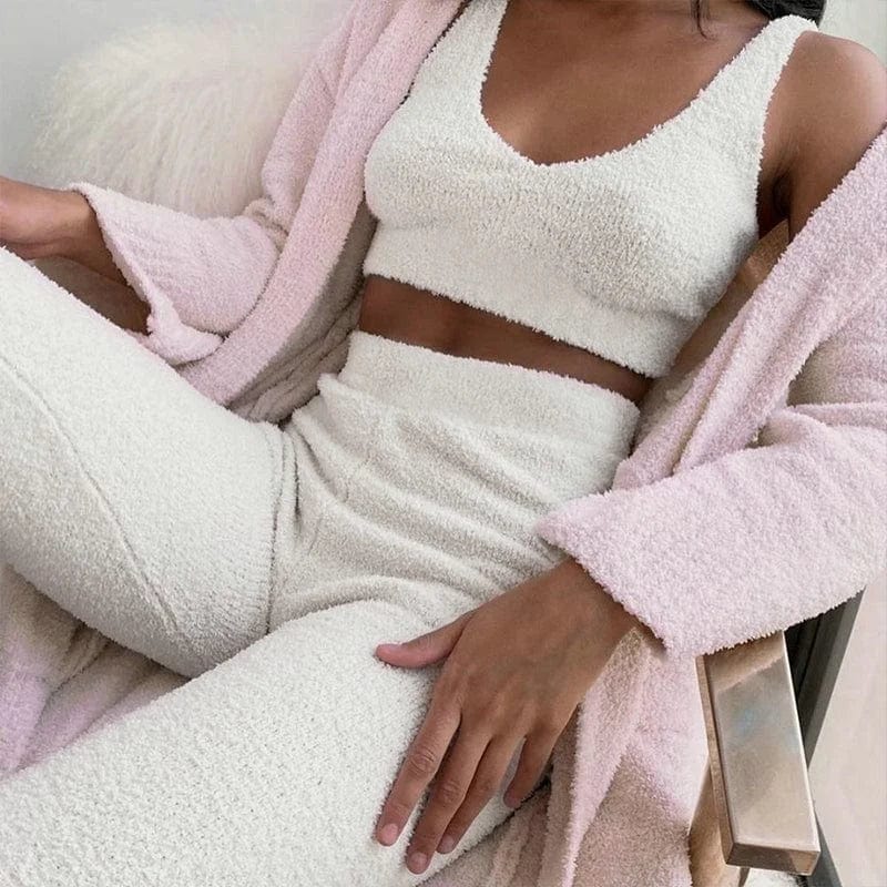 Woman wearing a fluffy white sports set with a crop top and high-waisted pants, paired with a light pink cardigan. Cozy loungewear fashion.