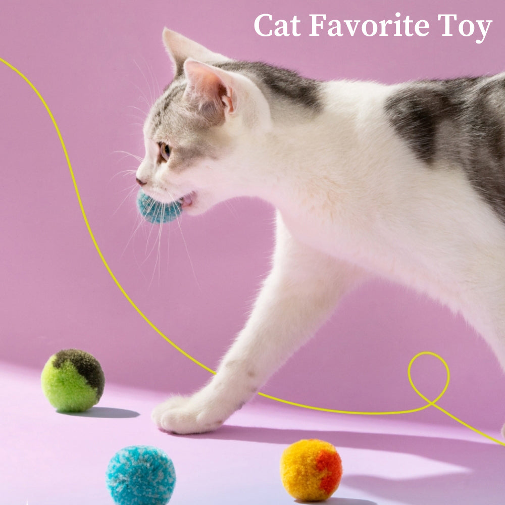 Cat playing with colorful plush balls on a pink background. Interactive cat toy, perfect for indoor play. Ideal for pet entertainment and exercise.