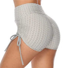 High-waisted gray textured sports shorts with ruched design and side tie detail, perfect for gym workouts and activewear fashion.