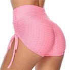 Pink high-waisted ruched sports shorts with side tie detail, textured fabric, perfect for gym workouts, yoga, and activewear fashion trends.