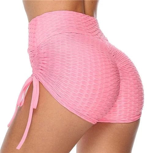 Pink high-waisted ruched sports shorts with side tie detail, textured fabric, perfect for gym workouts, yoga, and activewear fashion trends.