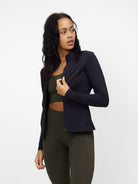 Woman wearing a black zip-up blouse over an olive green sports bra and leggings, showcasing stylish activewear fashion.