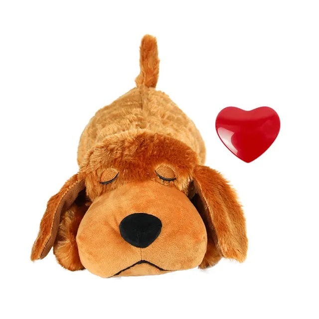 Brown plush dog toy with closed eyes, lying down next to a red heart. Soft stuffed animal, perfect for kids and dog lovers. Cute cuddly gift.