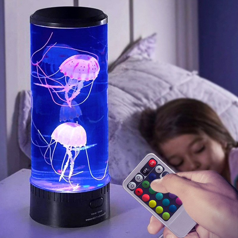 LED jellyfish lamp with remote control on a bedside table, featuring realistic floating jellyfish in a blue-lit cylindrical tank, perfect for bedroom decor.