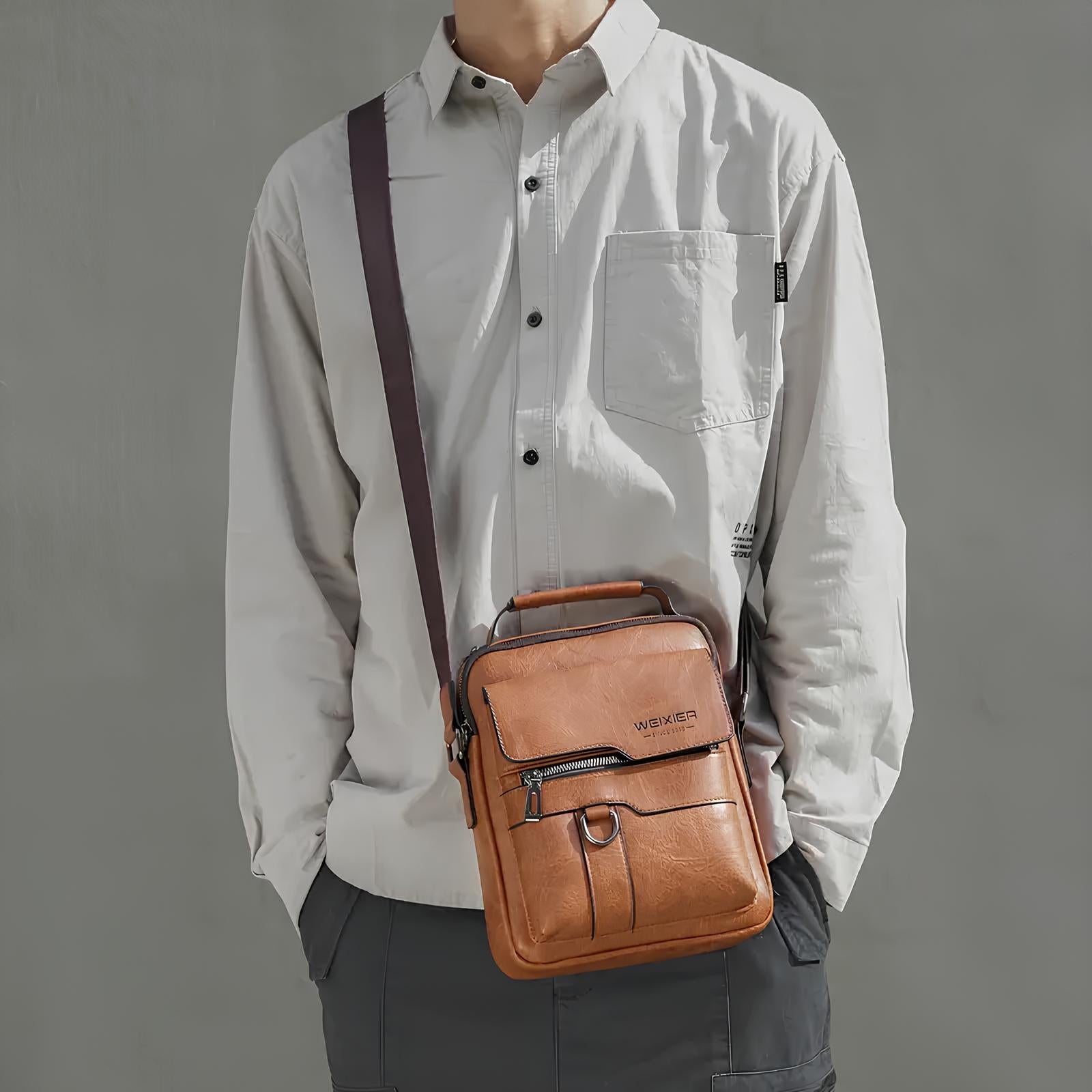 Man wearing a white shirt with a brown leather crossbody bag. Stylish men's fashion accessory, casual outfit, modern shoulder bag for everyday use.