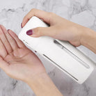 Hand using a white automatic soap dispenser on a marble countertop, dispensing liquid soap. Modern hygiene, touchless technology, bathroom accessory.