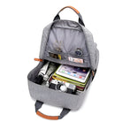 Open gray backpack with organized compartments, featuring a camera, tablet, notebook, and accessories. Ideal for travel and photography enthusiasts.