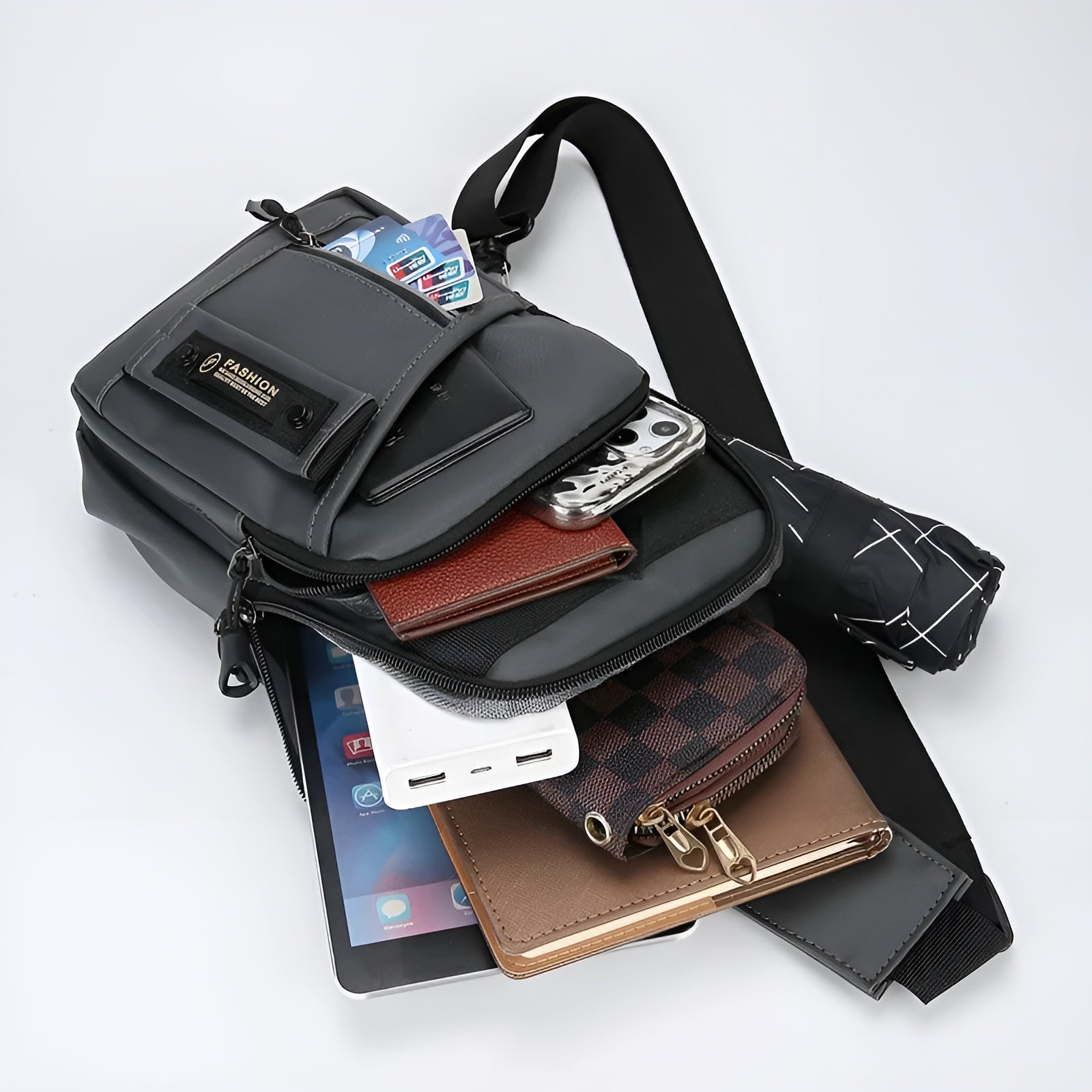 Crossbody bag with multiple compartments, showcasing organized essentials: smartphone, wallet, power bank, tablet, and umbrella. Ideal for travel and daily use.