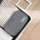 Open suitcase with neatly packed travel organizer and striped clothing on wooden floor. Efficient packing, travel essentials, luggage organization.