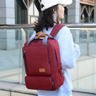 Woman wearing a stylish red backpack with multiple compartments, ideal for travel and school. Fashionable accessory for students and travelers.