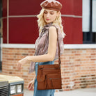 Fashionable woman with a brown leather crossbody bag, wearing a checkered top and beret, standing by a vintage car. Stylish urban outfit.