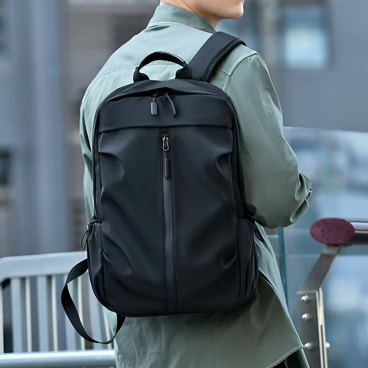 Sleek black backpack with multiple compartments, worn by a person in a green jacket, ideal for urban travel and daily commuting.