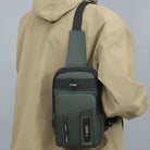 Green crossbody sling bag with multiple compartments, worn over a beige jacket. Stylish, functional design for travel and everyday use.