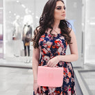 Woman in floral dress holding pink handbag in modern store; fashion shopping, stylish accessories, trendy outfit, retail display background.