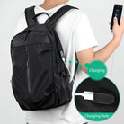 Black backpack with USB charging port, shown charging a smartphone. Features sleek design, durable material, ideal for travel and tech-savvy users.