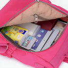 Open pink backpack with tablet, smartphone, tissues, and power bank inside. Ideal for travel and organization. Stylish and practical accessory.