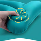 Hand pressing built-in pump on teal inflatable camping pillow, showcasing easy inflation feature. Ideal for outdoor travel, hiking, and backpacking.