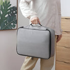 Person holding a sleek gray travel organizer bag with zipper, ideal for electronics and accessories storage. Modern design, portable, lightweight.