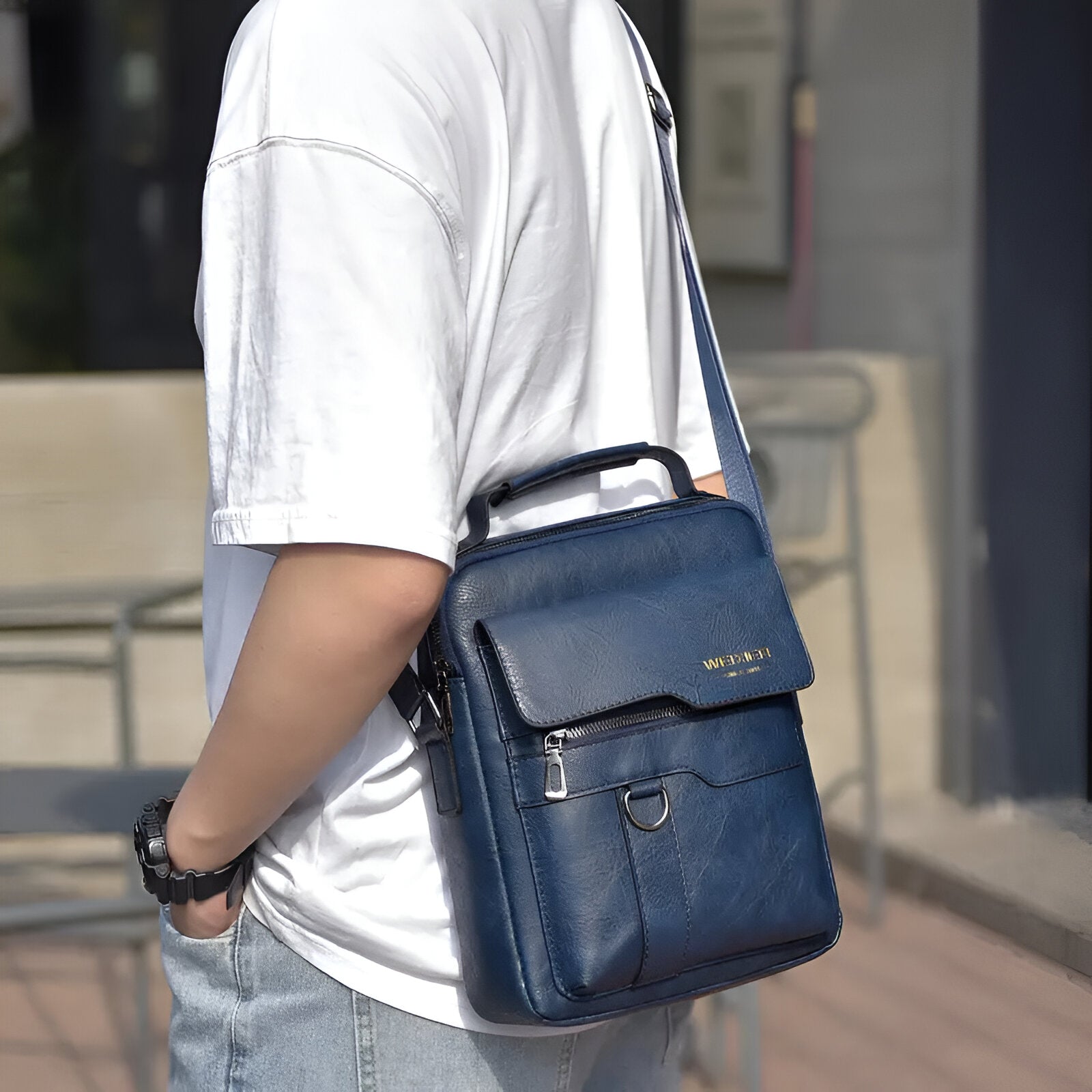 Man wearing a stylish blue leather crossbody bag with adjustable strap, front pocket, and gold logo. Perfect for casual outings and travel.