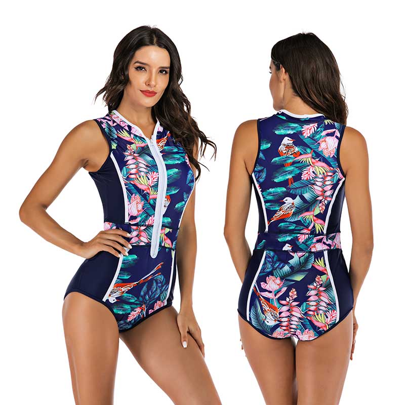 Women's navy blue one-piece swimsuit with tropical leaf print, front zipper, and sporty design. Perfect for beachwear and swimming activities.