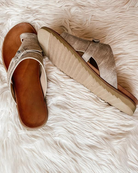 Women's metallic slide sandals with cushioned footbed and textured sole on a white faux fur background. Stylish summer footwear for casual wear.