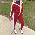 Red classic tracksuit set with white stripes, featuring a zip-up jacket and matching pants. Perfect for casual wear or athletic activities.
