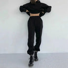 Casual black sweatshirt set with cropped hoodie and jogger pants, styled with black combat boots. Trendy women's loungewear fashion outfit.