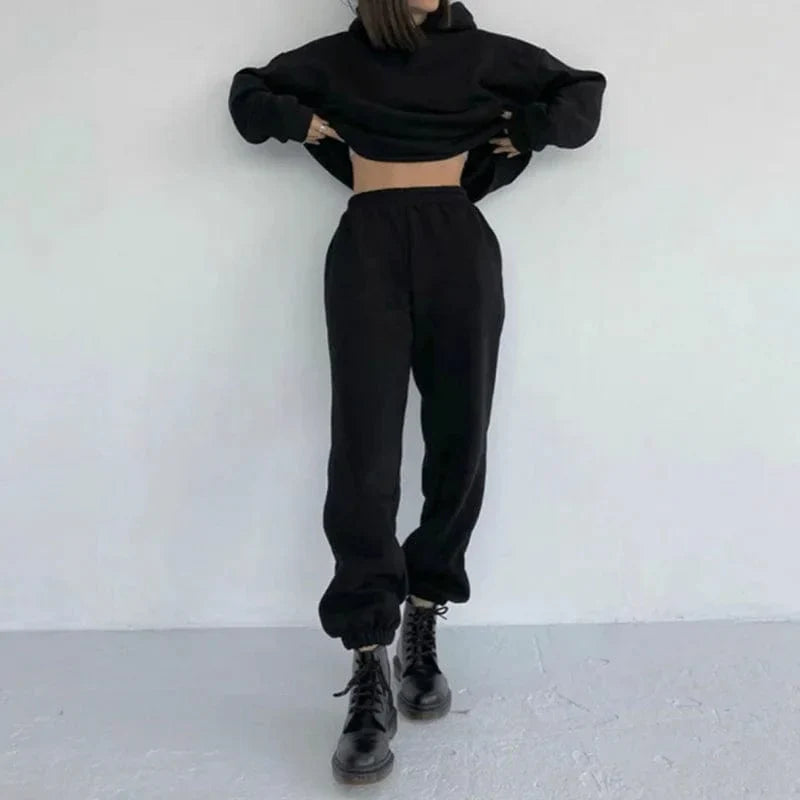 Casual black sweatshirt set with cropped hoodie and jogger pants, styled with black combat boots. Trendy women's loungewear fashion outfit.