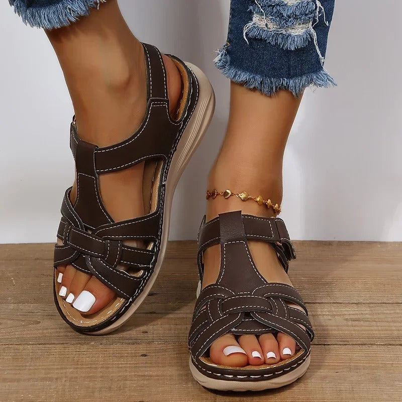 Women's brown leather sandals with white stitching, featuring a comfortable sole and open-toe design. Perfect for casual summer fashion.