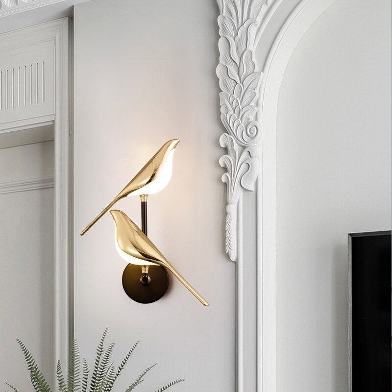 Gold-plated bird design LED wall lamp on ornate white wall; modern lighting fixture for living room, bedroom, hallway decor.