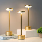 Modern gold LED table lamps on a white surface, featuring sleek cylindrical design and warm lighting, ideal for contemporary home decor and ambient lighting.