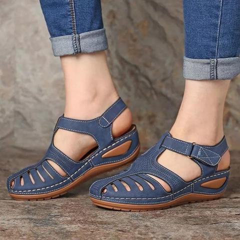 Blue orthopedic sandals with low heels, breathable design, and correction function, worn with rolled-up jeans. Ideal for comfort and support.