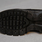 Close-up of a black rubber shoe outsole with textured tread pattern, designed for enhanced grip and durability on various surfaces.